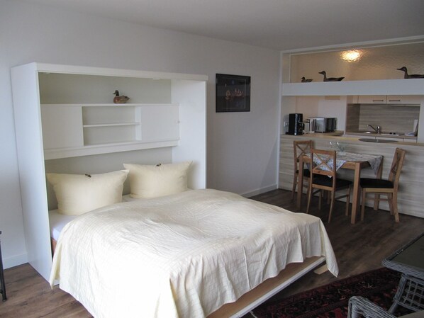 A compact room with a bed, a small dining area, and a kitchenette. - Hanseatenhaus Apartment 67 - 1 room app. with open American kitchen (Sylt)