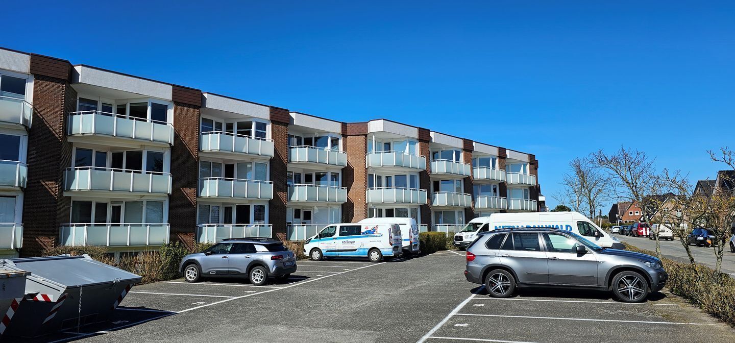 A multi-story building with a parking lot in front.
