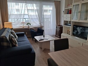 A modern living room with a sofa, a coffee table, a TV, and a cabinet.