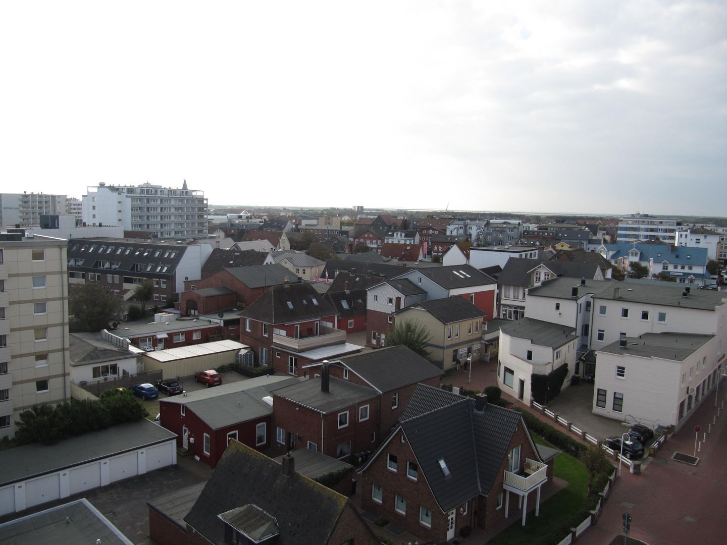 A residential area with a mix of houses and apartment buildings, featuring a variety of roof styles and building materials.
