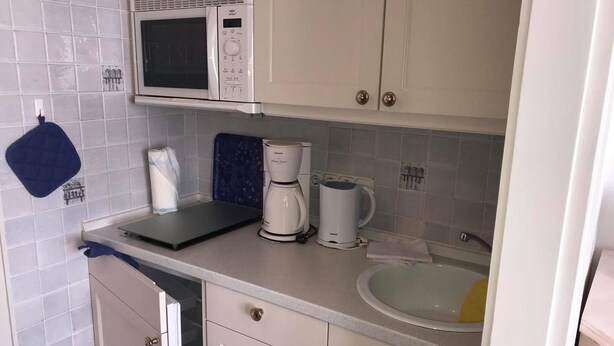 Een kleine keuken met een magnetron, koffiezetapparaat en een spoelbak.