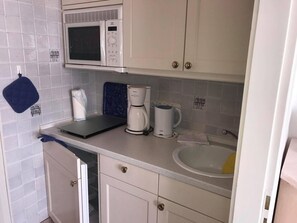 A compact kitchen with a microwave, coffee maker, and a sink.