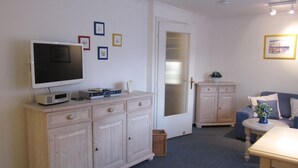 Een woonkamer met een televisie, een kast en een bank.
