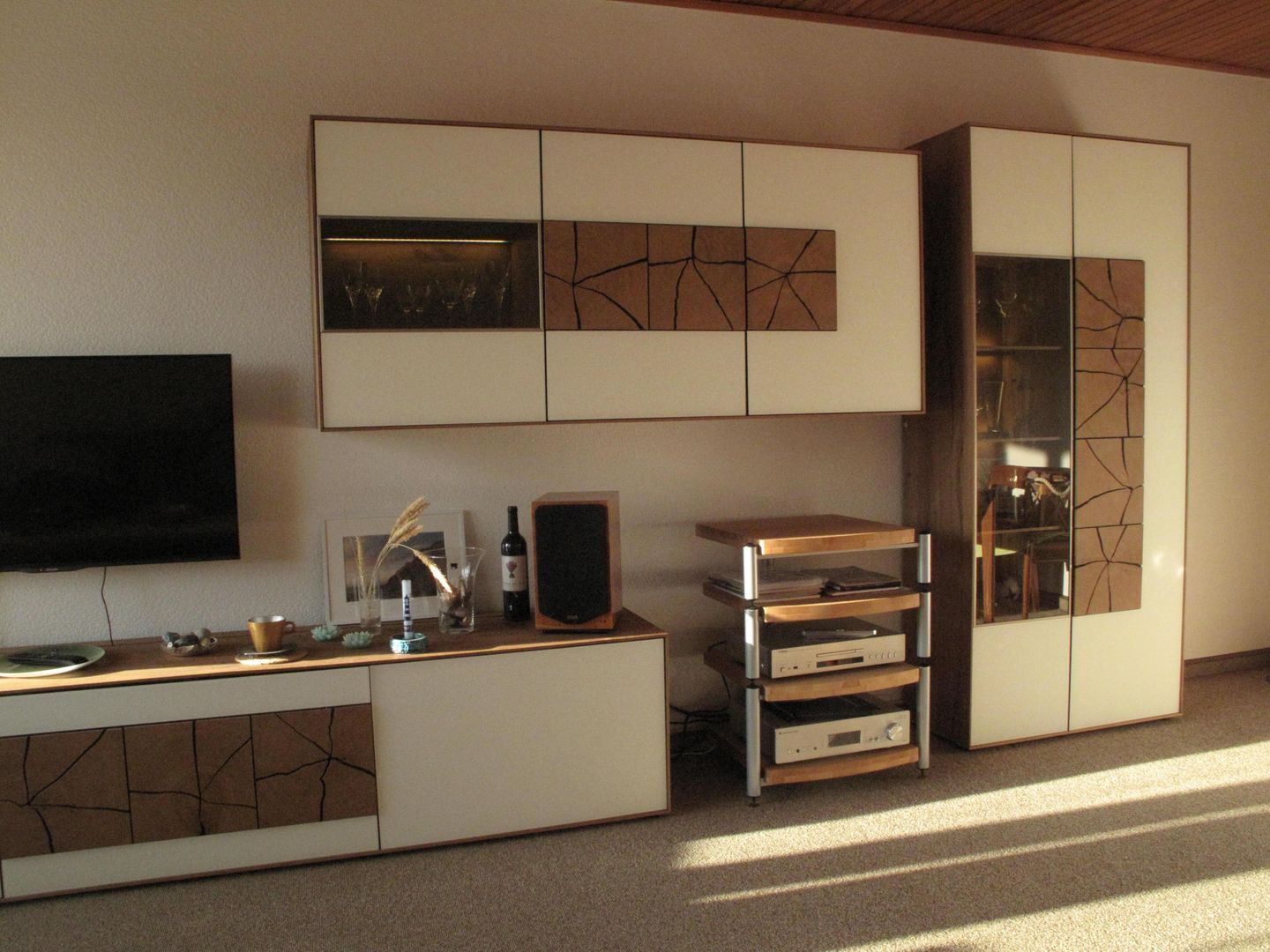 A modern living room with a flat-screen TV, a wooden coffee table, and a built-in entertainment unit with speakers.