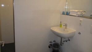 A bathroom with a white sink, a mirror, and a towel rack with folded towels. - House Boysenstr.7 App. 6 - 2 room apartment in Boysenstr. 7 (Sylt)