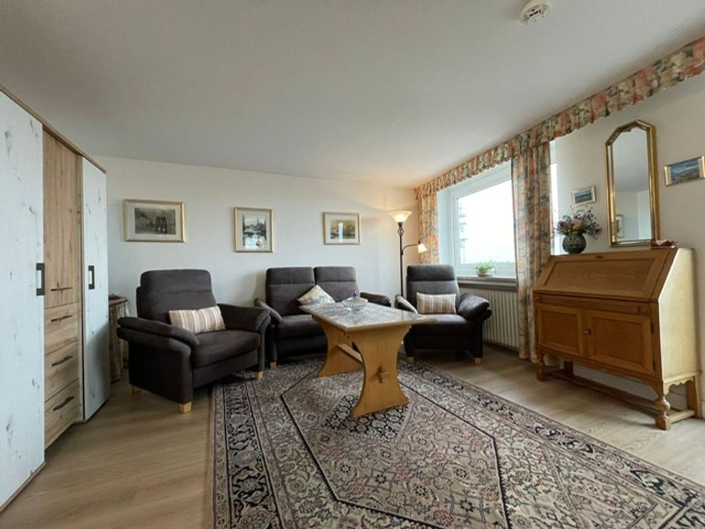 A living room with two sofas, a coffee table, a wooden cabinet, and a large rug.