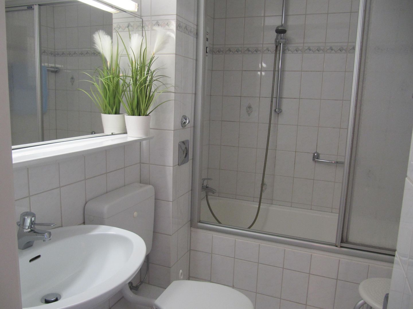 A bathroom with a sink, toilet, and shower area.