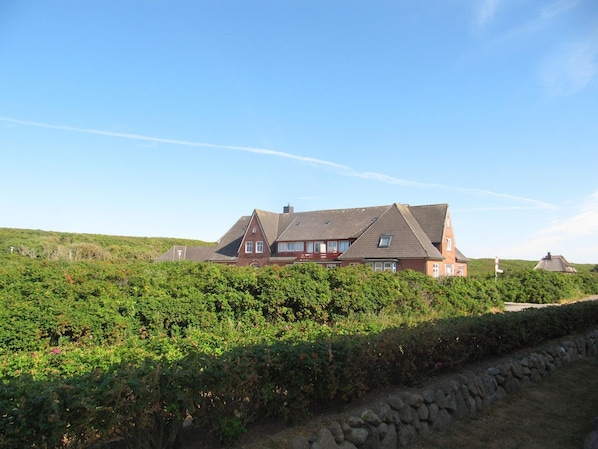 A large house with a sloped roof, surrounded by a vineyard.