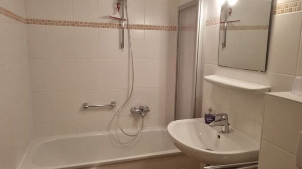 A bathroom with a bathtub, a shower, and a sink. - Undine House, Apt. 6 - 3-room apartment on Norderstr. (Sylt)