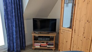 A living room with a television on a wooden stand, a blue sofa, and a wooden cabinet.