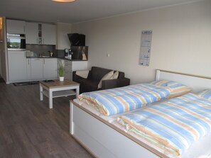 Une pièce de taille modeste comprenant un lit, un canapé, une petite table et un coin cuisine.