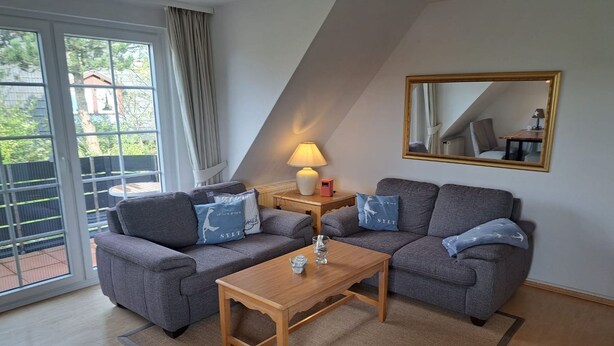 A modern living room with a grey sofa set, a wooden coffee table, and a lamp. - Halemdüür 9 An apartment no. 2 - 2 room apartment in the south of Westerland. (Sylt)