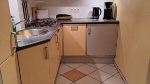 A compact kitchen with a sink, stove, and cabinets. - Sylter Residenz App.33 - 2 room apartment in Bomhoffstr. 5 (Sylt)