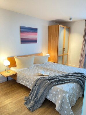 Une chambre à coucher avec un lit, des tables de chevet, une armoire en bois et un tableau accroché au mur.