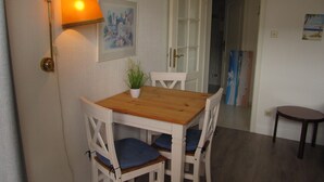Een eethoek met een houten tafel en witte stoelen, een wandlamp en een schilderij.