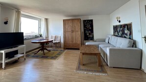 Ein Wohnzimmer mit Fernseher, Sofa, Holzschrank und Kunstwerken.