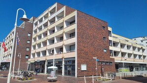 Een meerlaags gebouw met een bakstenen gevel, balkons en een entree op de begane grond.