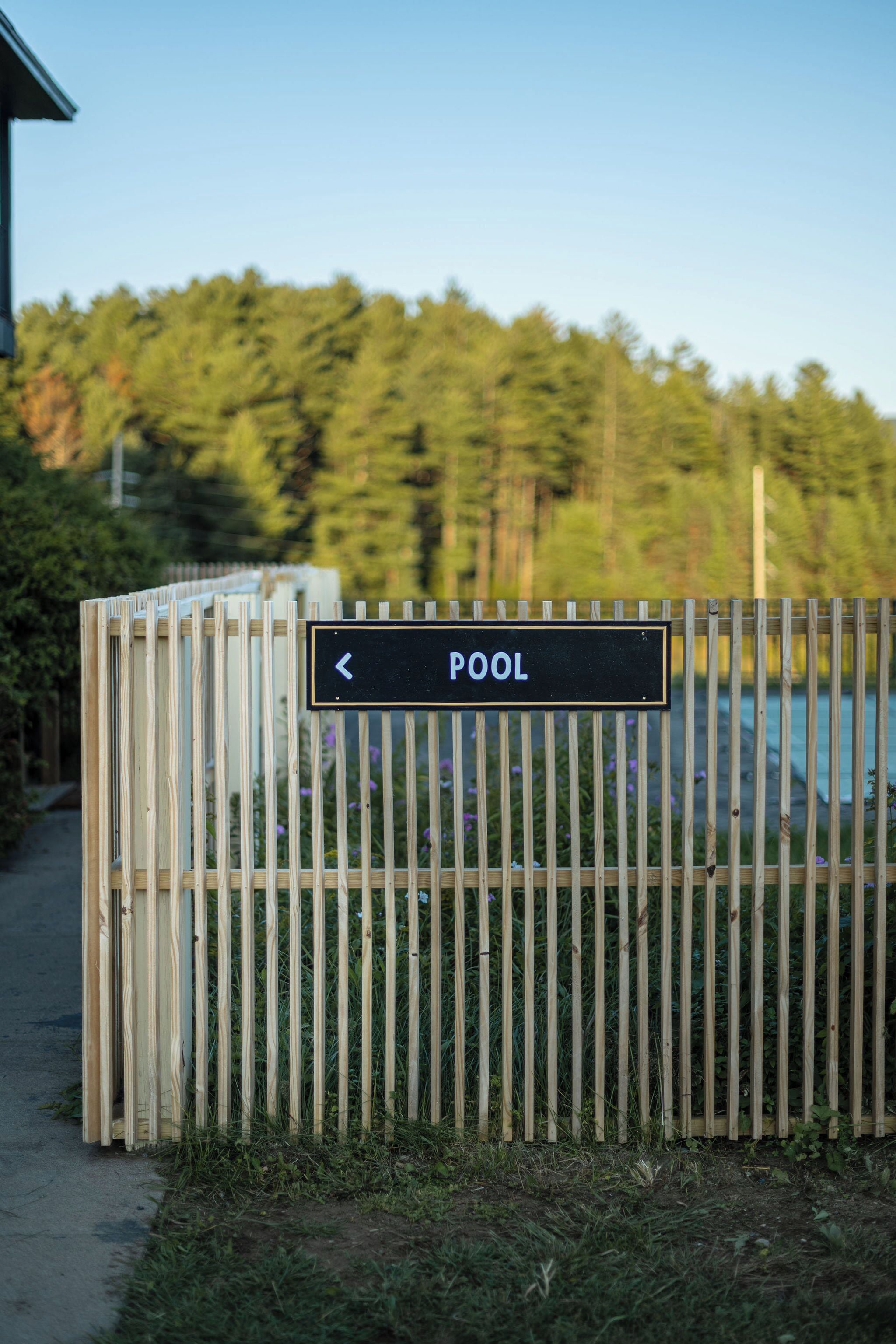 A wooden fence with a sign indicating a pool direction.