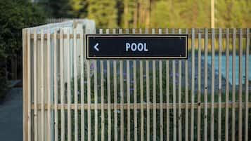 A wooden fence with a sign indicating a pool direction.