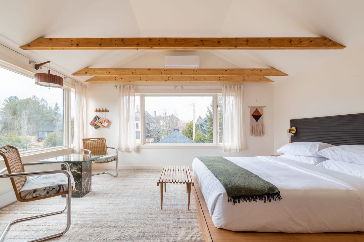 A bedroom with a bed, a chair, a table, and a window.