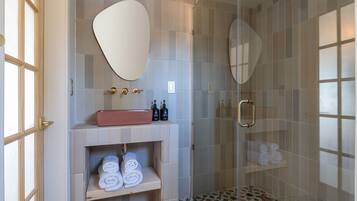Un bagno moderno con un mobile lavabo, uno specchio grande, una doccia con porta in vetro e un pavimento decorato.