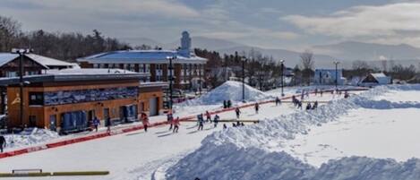 A ski resort with a snow-covered slope, a building with a blue roof, and a clear sky.