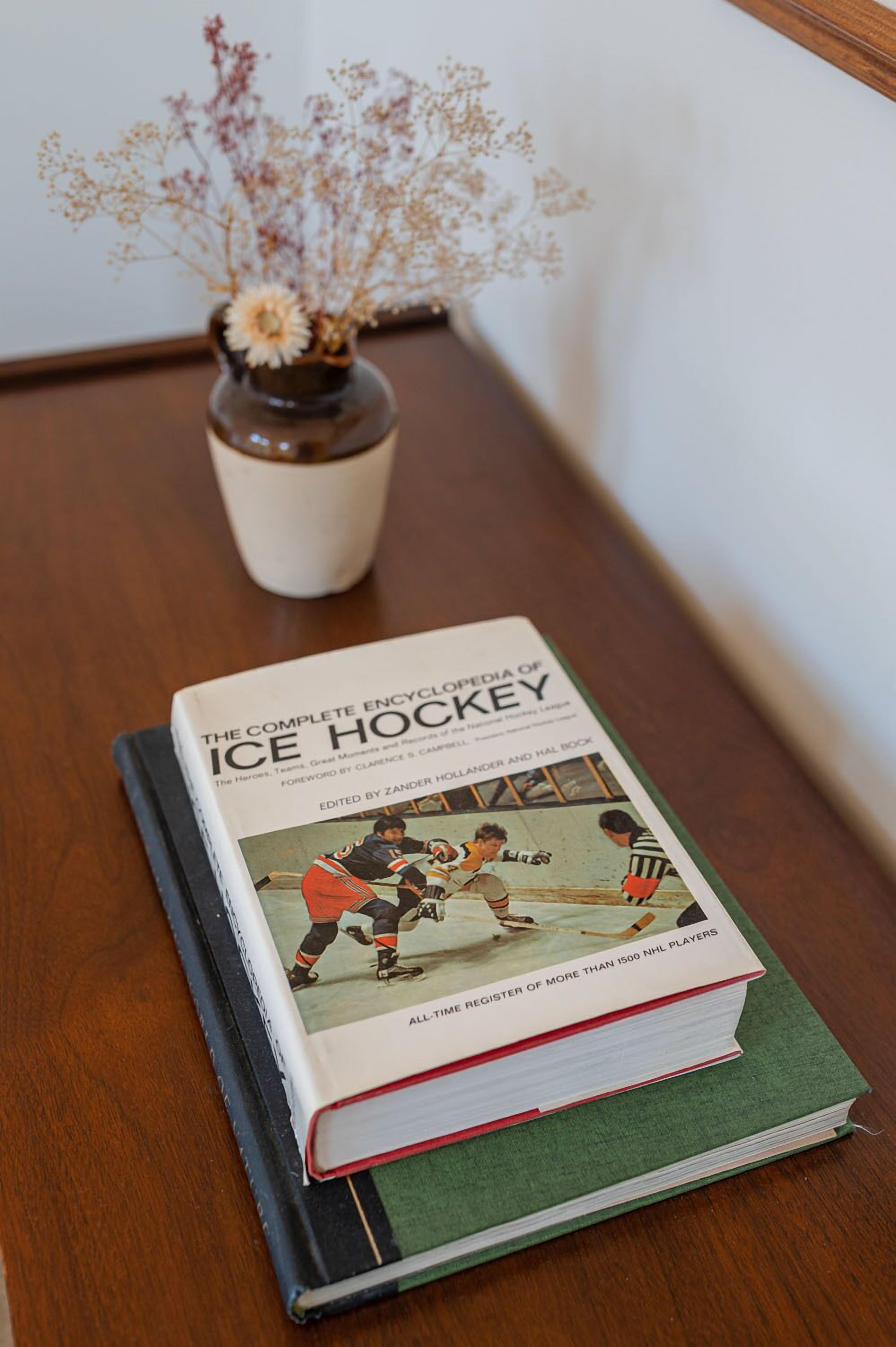 Un livre intitulé « L’encyclopédie complète du hockey sur glace » est posé sur une table en bois.