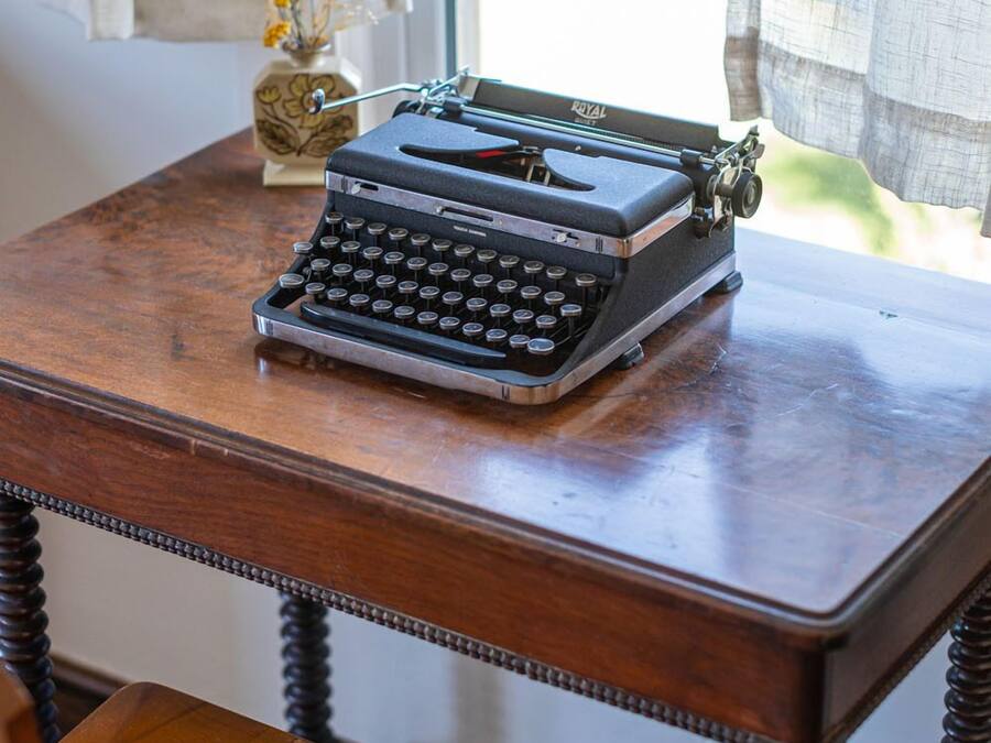 A vintage typewriter on a wooden table with a chair in front.
