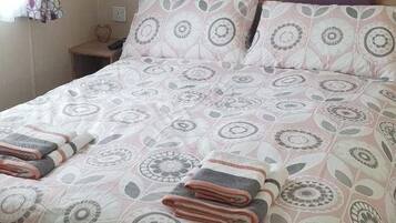A neatly made bed with a patterned bedspread, two pillows, and folded towels.