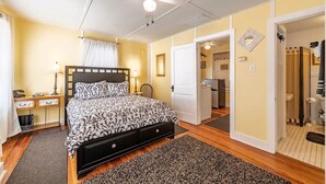 Een slaapkamer met een bed, nachtkastjes, een plafondventilator en een deur naar een badkamer.