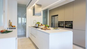 Une cuisine moderne dotée d’un îlot central, d’appareils électroménagers en acier inoxydable et donnant sur la salle à manger.