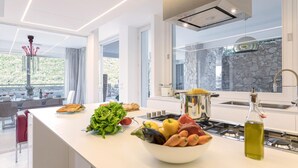 Une cuisine moderne dotée d’un grand îlot central, d’un mur en pierre et offrant une vue sur l’extérieur.