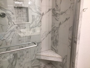 Ein Badezimmer mit Marmorwänden und einer Duschkabine aus Glas.