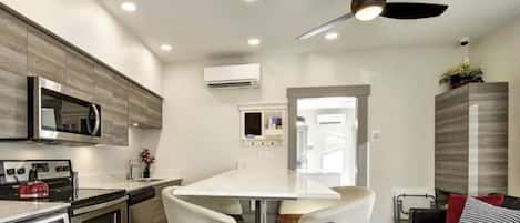 Cozinha moderna com ilha central, eletrodomésticos embutidos e ventilador de teto.