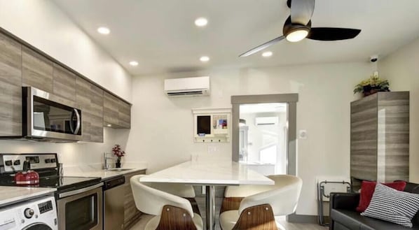 Cozinha moderna com ilha central, eletrodomésticos embutidos e ventilador de teto.