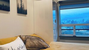 Ett sovrum med en säng, ett fönster med utsikt och en väggmonterad luftkonditioneringsanläggning.