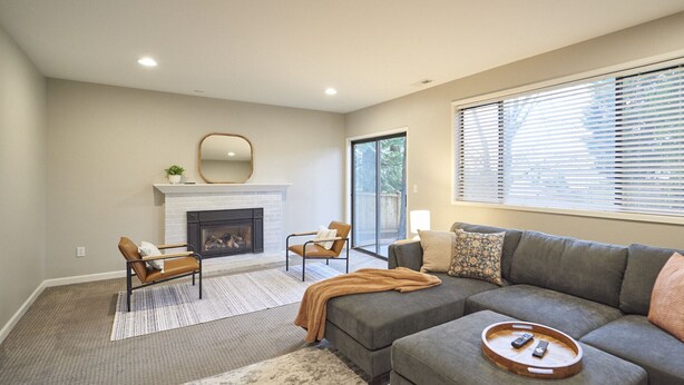 A living room with a fireplace, two armchairs, a sofa, and a large window with blinds. - Experience Woodinville Wine Country/Downtown Bothell (BOTHELL)