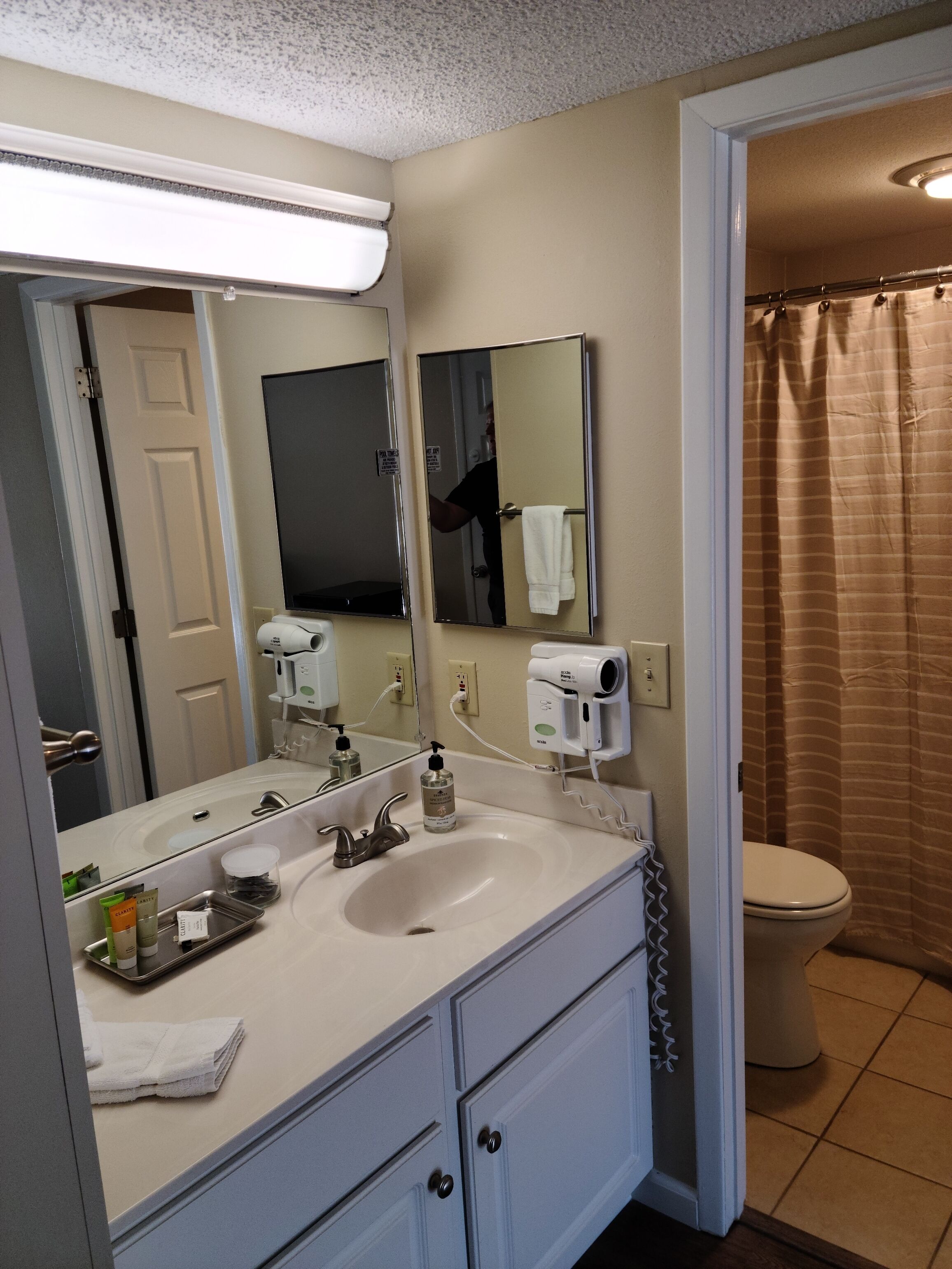 A bathroom with a sink, mirror, towel rack, and a shower curtain.