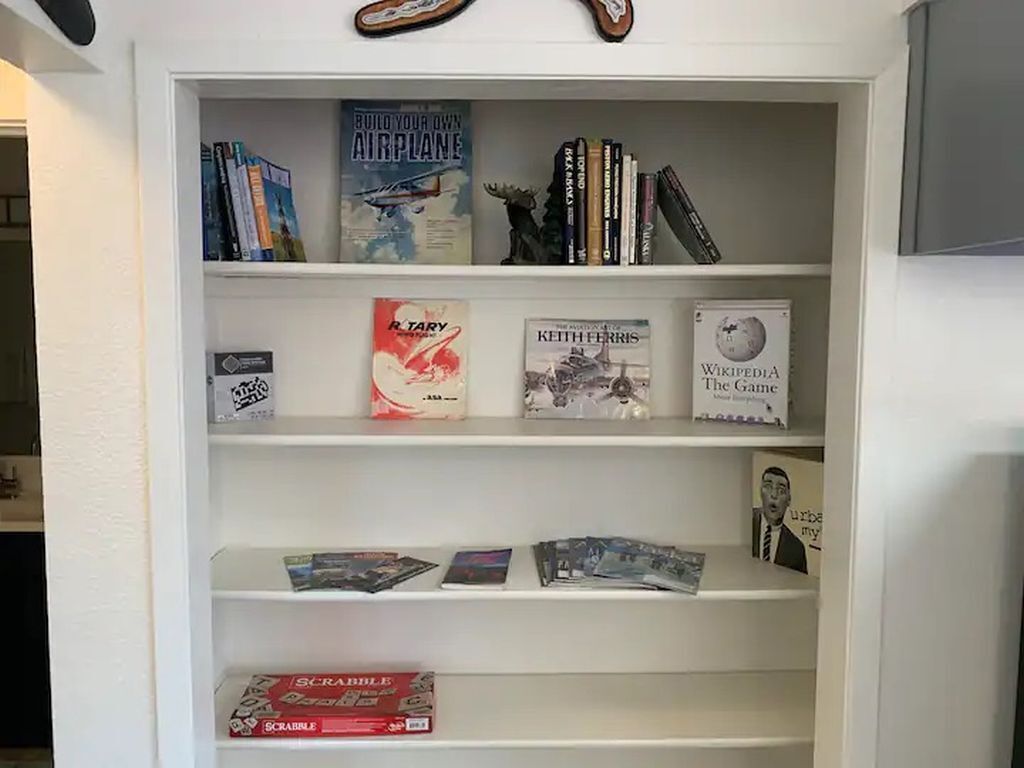 En bokhylla med olika böcker och spel, bland annat ”Bygg ditt eget flygplan” och ”Scrabble”.