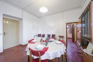 A dining area with a round table set for four, chairs, a chandelier, and a staircase leading to another level. - Gufo- Flowers -100m  Near Lake, Toscolano Maderno, Italy (Toscolano Maderno)