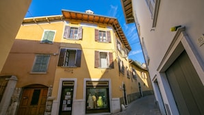 A narrow street with a yellow building featuring a shop window with mannequins. - Gufo - Navy- 100m  Near Lake, Toscolano Maderno, Italy (Toscolano Maderno)