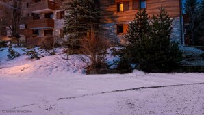 Un edificio de madera de varios pisos con balcones, rodeado de nieve y árboles.