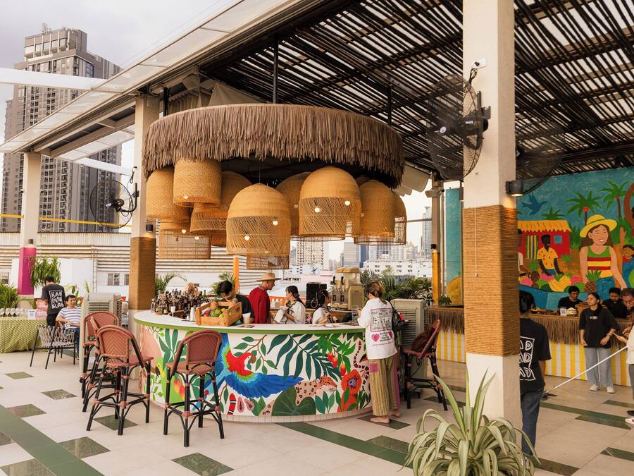 Un restaurante con temática tropical, que presenta mobiliario de mimbre y un mural con fauna tropical.
