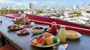A balcony with a city view, featuring a table with various dishes and drinks.