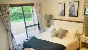 A bedroom with a bed, two bedside tables, a lamp, and a window with curtains. - Martha's ......... Your hideaway in the highlands. (Burradoo)