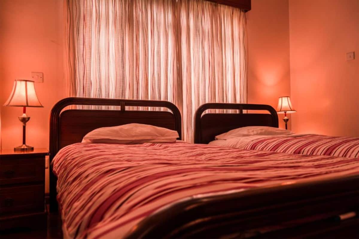 A double bed with a striped bedspread in a room with two bedside tables, each with a lamp.