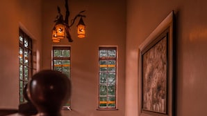 A hallway with two windows, a framed artwork on the wall, and a decorative light fixture. - Oilepo Cottage (Naivasha)