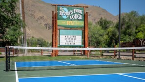 Una cancha de tenis con un cartel que dice 'River's Fork Lodge' y un mensaje de bienvenida para la Reunión Familiar Stephens.
