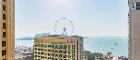 A high-rise hotel with a view of the sea and a Ferris wheel in the distance.