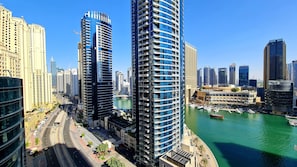 A high-rise building with a modern architectural design, situated next to a body of water with boats docked.